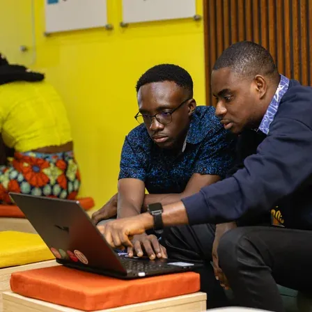 A mentor and a founder working through a problem at a laptop.